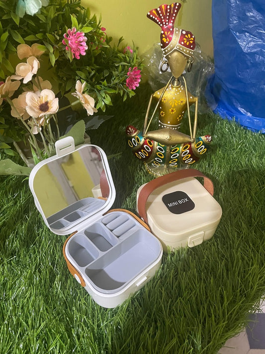 Compact and portable mini jewellery box with mirror and multiple compartments to organize earrings, necklaces, rings, and more. Ideal for travel and safekeeping. Available in random colors.