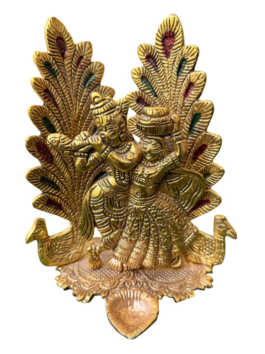 Peacock Design Radha Krishna Idol Showpiece with Diya. Ideal for Puja & Home Decor. Crafted in Metal with a Gold Finish. Size: 8x6 inches.